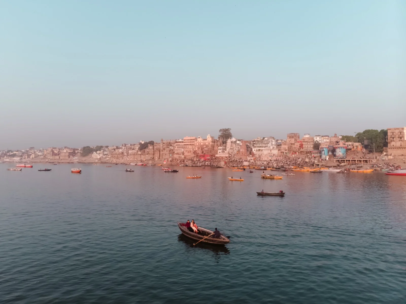 Couple on a wooden boat facing the Varanasi ghats at sunrise