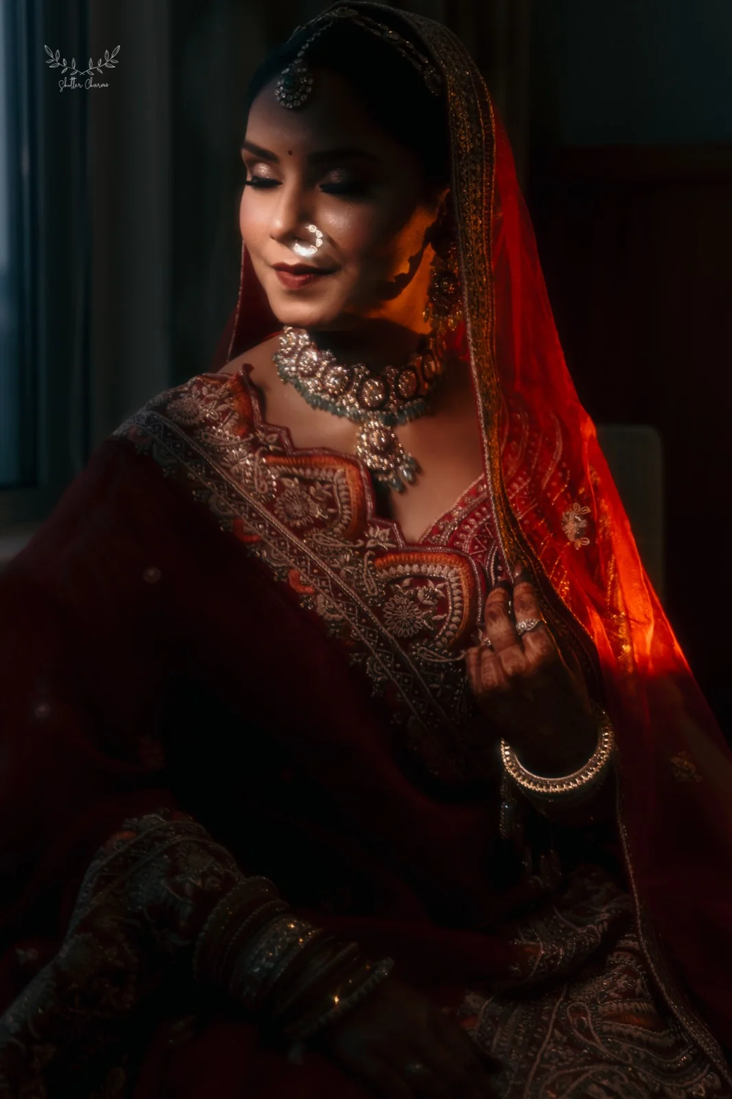 Bride in red lehenga and kundan jewellery in dramatic window light