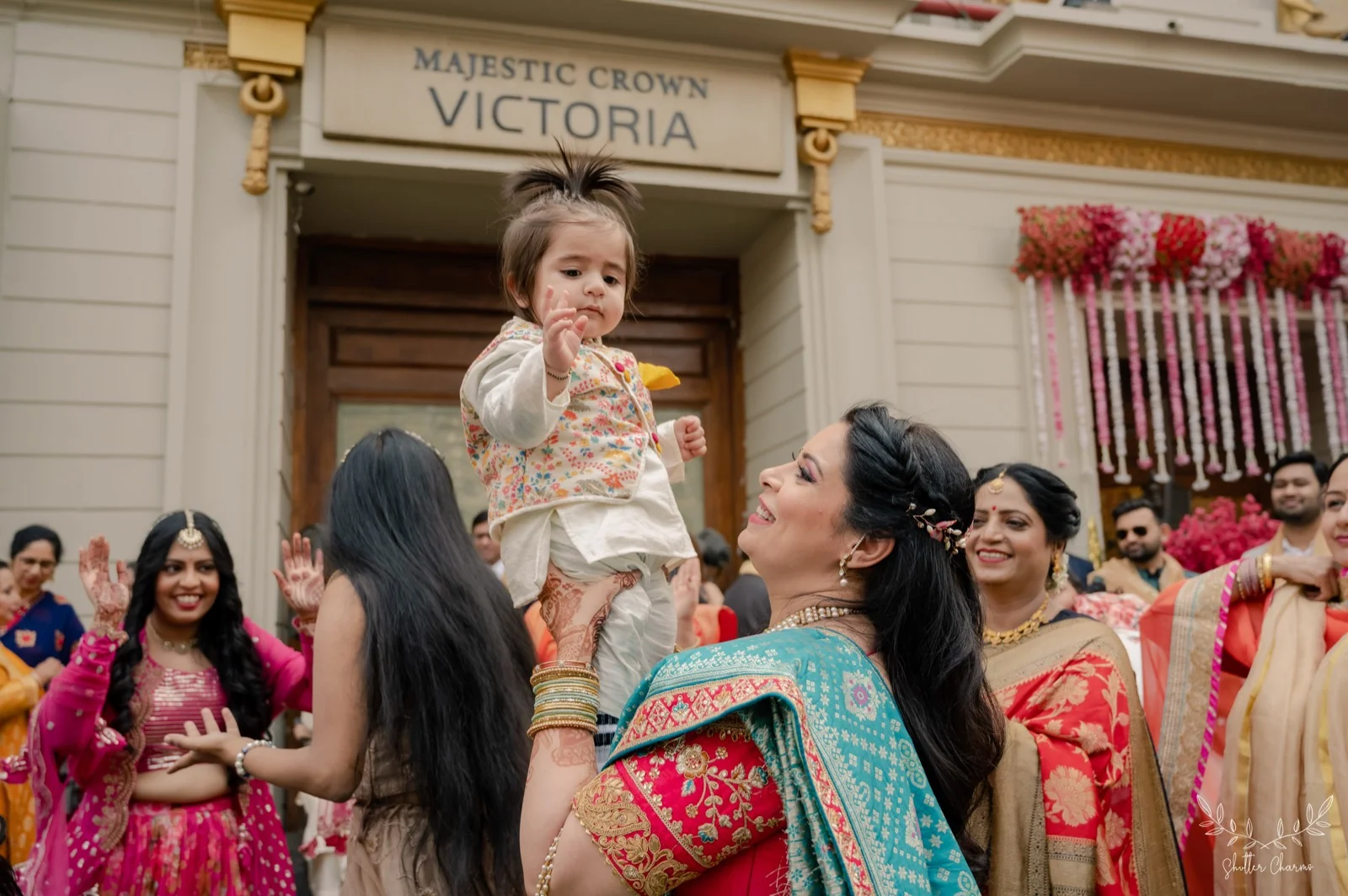 Guest lifting a toddler amid dancing family at wedding venue entrance