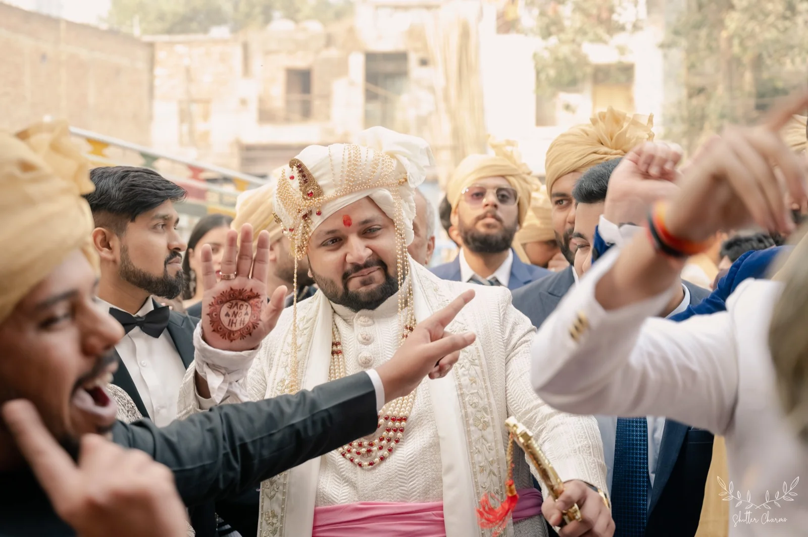 Groom in ivory sherwani and safa celebrating amid lively baraat
