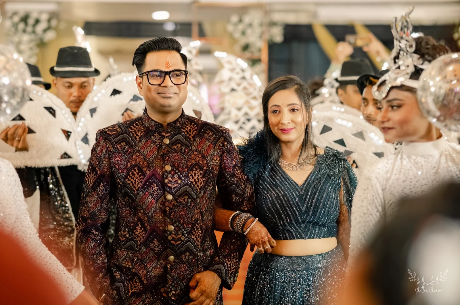 Couple making grand reception entry escorted by feathered carnival dancers