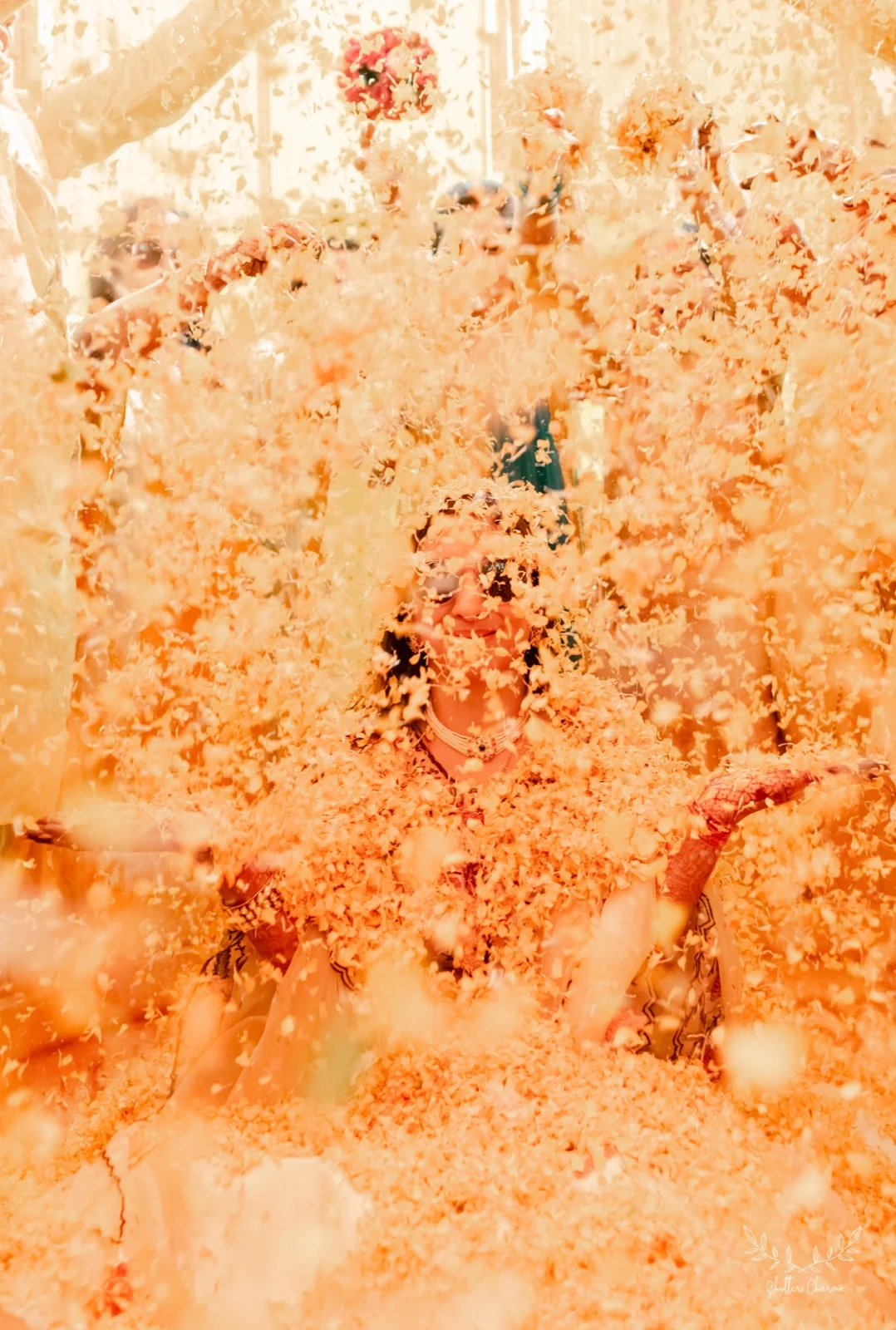 Bride smiles through a golden cascade of flower petals