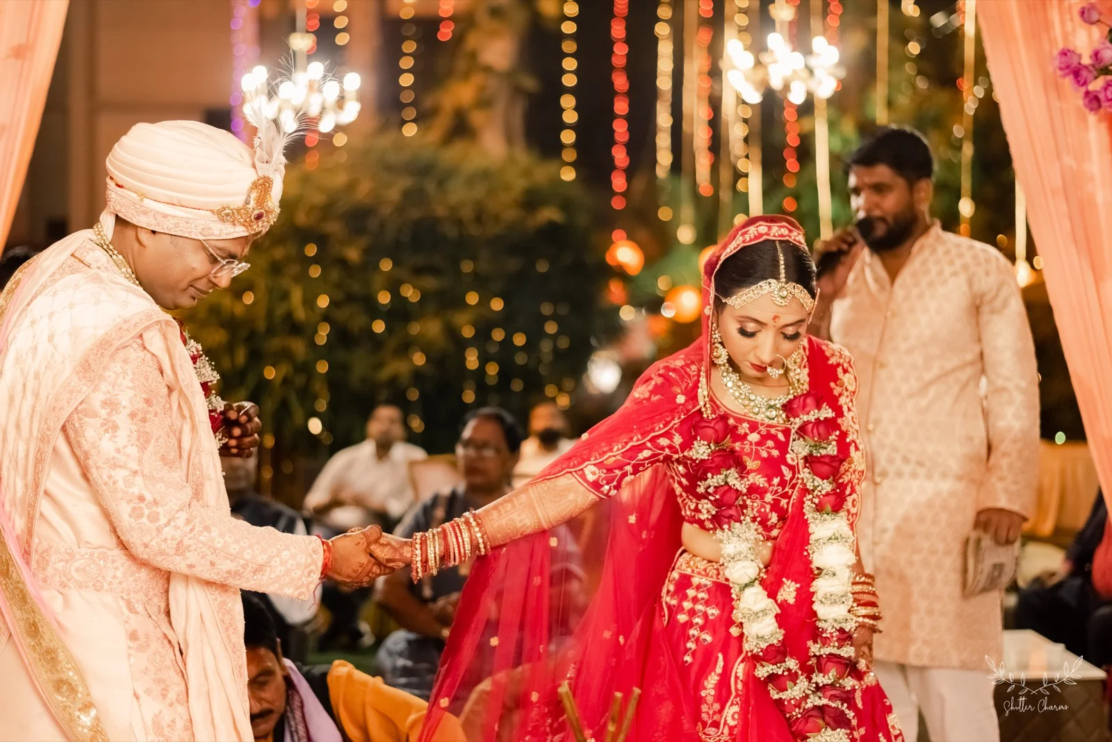 Groom holding bride's hand as she performs wedding rituals