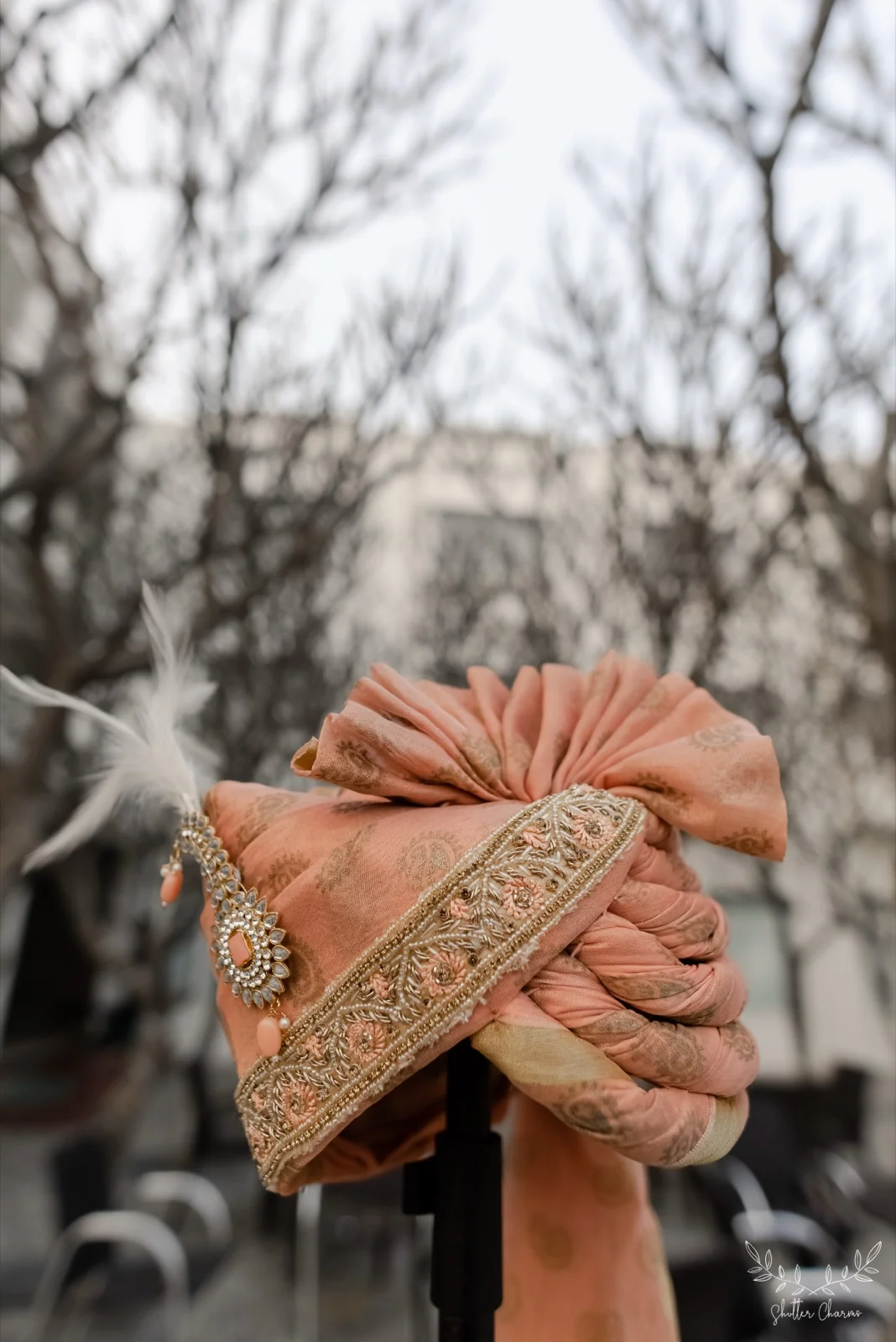 Groom's peach safa with jewelled kalgi displayed outdoors