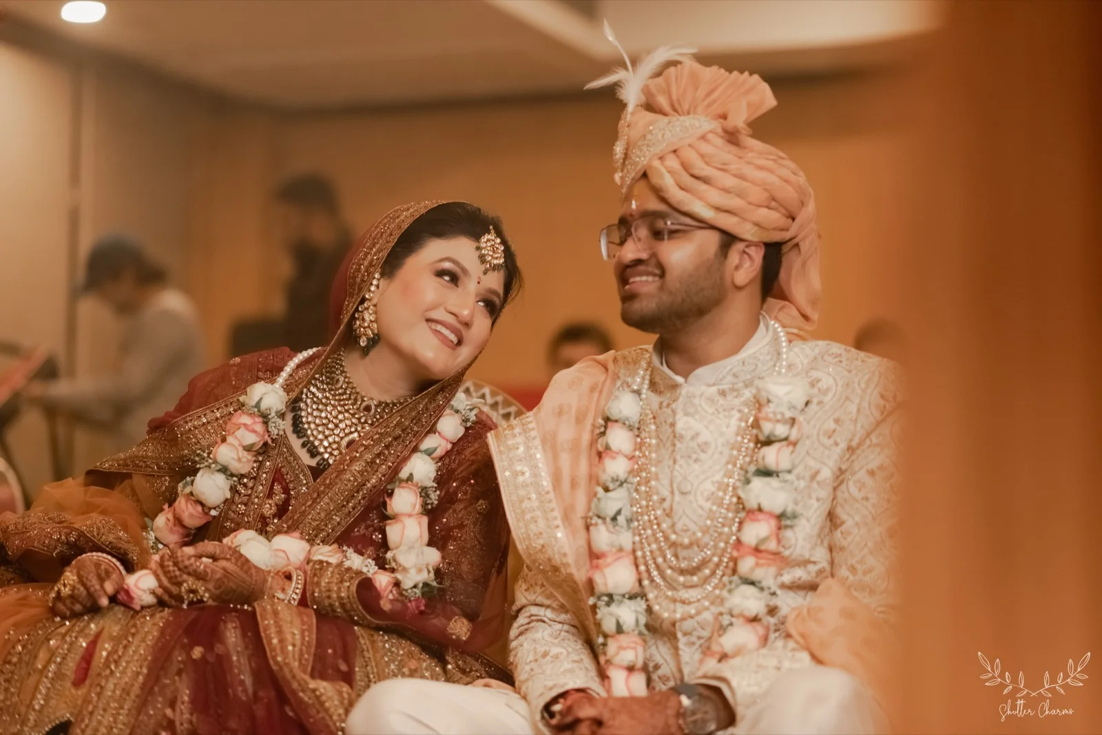 Bride and groom in wedding attire sharing a joyful glance after varmala