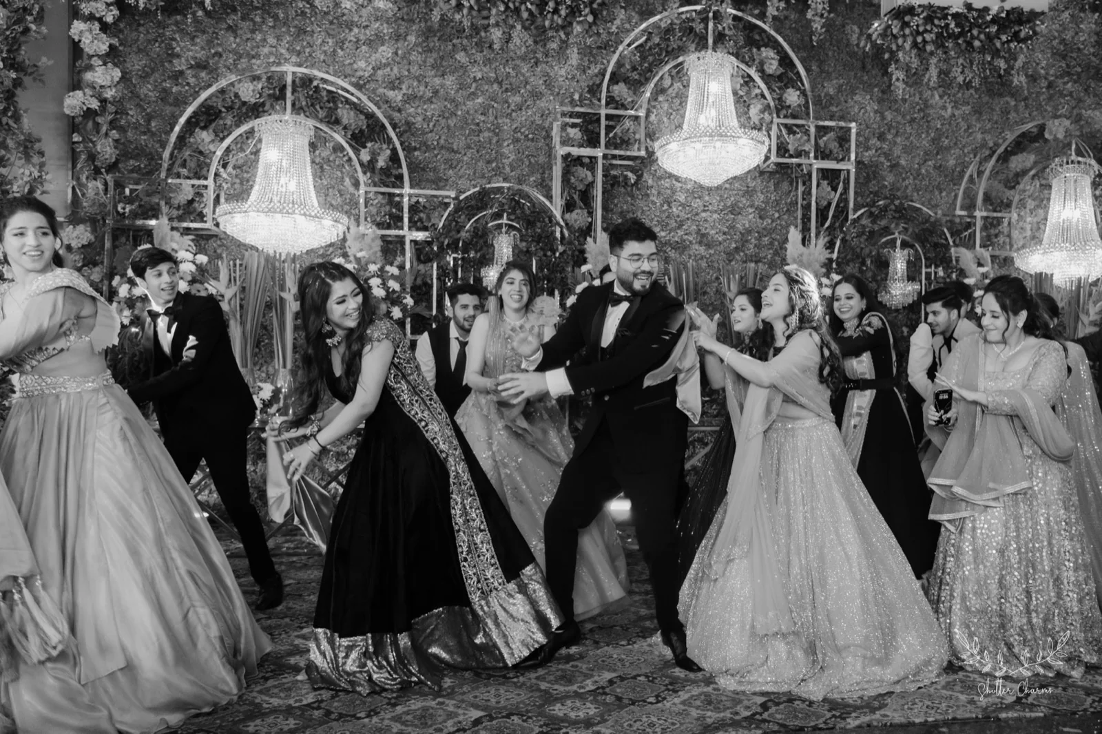 Friends dancing with the groom at a chandelier-lit sangeet night