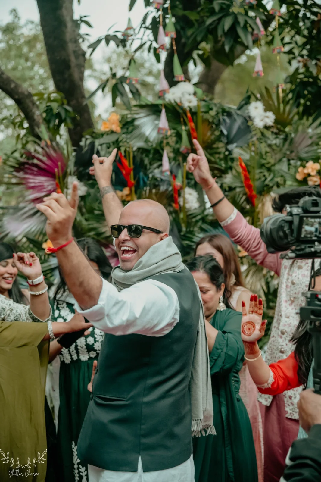 Guests dancing with raised hands at festive outdoor mehendi celebration